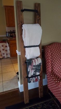 a wooden ladder with towels hanging from it's sides in a living room next to a couch