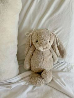 a stuffed rabbit sitting on top of a bed next to a pillow