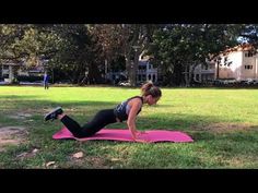 a woman is doing push ups on a pink mat in the middle of a park