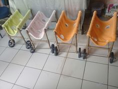 four baby strollers are lined up in a row on the floor next to a tiled floor