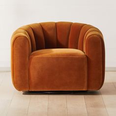 an orange chair sitting on top of a hard wood floor next to a white wall