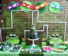 a green table topped with lots of food and desserts next to a brick wall