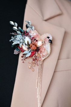 a boutonniere decorated with flowers and pearls on the lapel of a suit