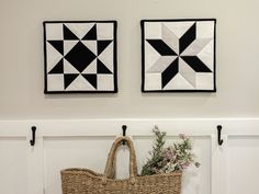 two black and white quilts hang on the wall above a wicker basket with flowers in it