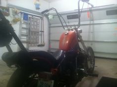 a red motorcycle parked in a garage next to a wall