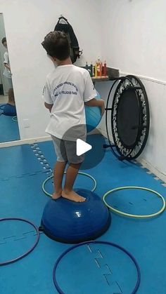 a little boy standing on top of a blue ball