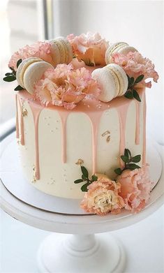 a white cake with pink flowers and macaroons on top