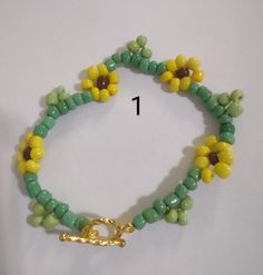 a green and yellow beaded bracelet with a gold clasp on the end is shown