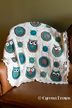 a crocheted owl afghan sits on a brown leather chair next to a wooden headboard