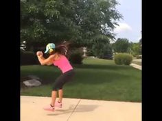 a woman in pink shirt and black pants playing with a frisbee on sidewalk