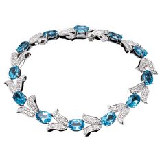 14k white gold bracelet. This beautiful bracelet features oval faceted, medium blue color blue topaz stones, approximately 10.45 TCW, prong set, alternating with tulip shaped links set with accent diamonds, 1.10 TCW. The bracelet has a hidden box style clasp, with a figure eight safety. Marks: 14k, 585 Dimensions: 6 7/8" long x 7/16" wide Weight: 10.8 gross dwt Condition: Surface scratches Blue Topaz Stone, White Gold Bracelet, Topaz Stone, Diamond Set, White Gold Diamonds, Medium Blue, Beautiful Bracelet, Link Bracelets, Prong Setting