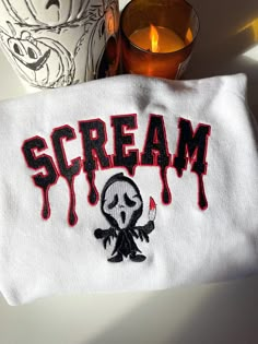 a white towel with the word scream on it next to a candle and some glasses