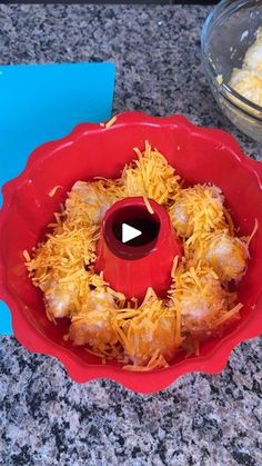 a red bowl filled with food sitting on top of a counter next to a glass bowl