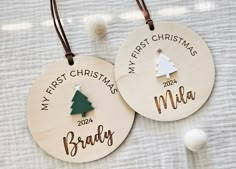 two personalized wooden christmas ornament hanging on a white blanket with pom poms