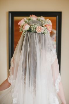 a woman wearing a veil and flowers on her head is looking at herself in the mirror