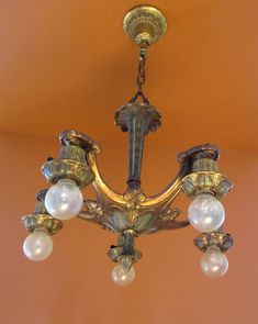 a chandelier hanging from the ceiling in a room with orange walls and gold trim