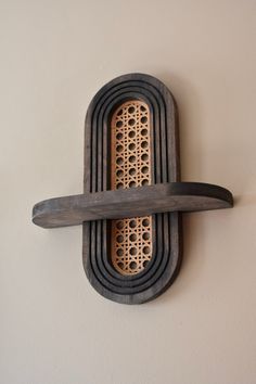 a wooden object with holes in it hanging on the wall next to a white wall