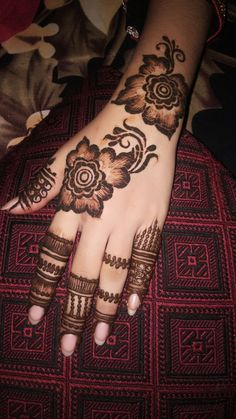 a woman's hand with hennap and flowers on her hands, showing the intricate