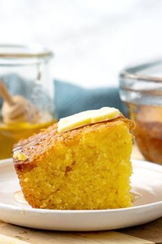 a piece of cake sitting on top of a white plate next to a glass jar