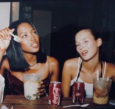 two young women sitting at a table with drinks and sodas in front of them