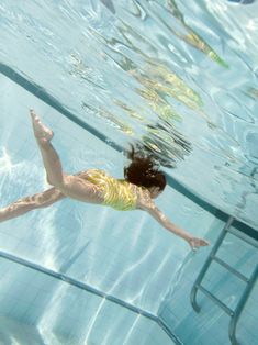 a woman in a yellow swimsuit swimming under water