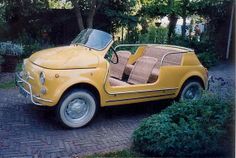 an old yellow car is parked in the driveway