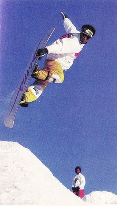 a man flying through the air while riding a snowboard on top of a snow covered slope