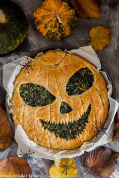 a pumpkin pie with eyes on it surrounded by autumn leaves and pumpkins in the background