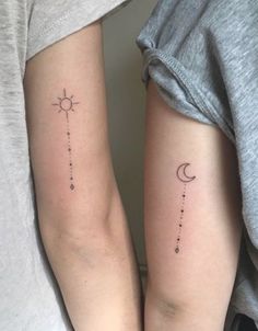 two people with matching tattoos on their arms, one is holding the other's arm