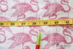 a measuring tape is next to a green and red pen on a pink floral print fabric