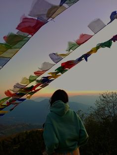 a woman standing on top of a hill next to colorful flags flying in the air