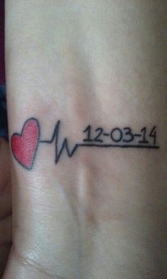 a small wrist tattoo with a heart and heartbeat on the left side of the arm