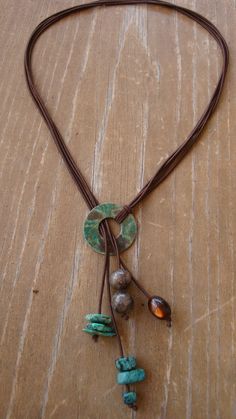 a necklace with beads and leather cord on a wooden surface