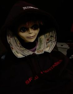 a doll wearing a black hoodie with money on it's chest and eyes