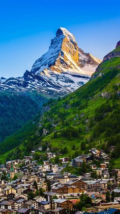 the mountains are covered in snow and green grass, with small houses on each side