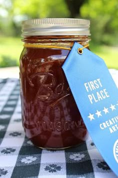 a mason jar with a blue label on it sitting on a checkered table cloth