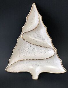 a white ceramic christmas tree dish on a black background with the shape of a leaf