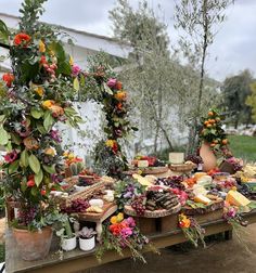 an assortment of food is displayed on a wooden table with potted plants and flowers