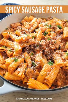 a skillet filled with pasta and meat sauce on top of a wooden table in front of the words spicy sausage pasta