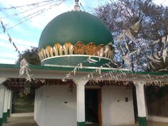 a green and white building with birds flying in the air over it's roof