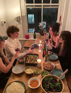 a group of people sitting around a table with food and wine