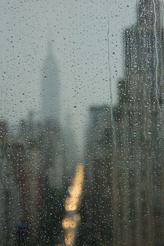 rain drops on the window with an image of a city in the background and a quote written