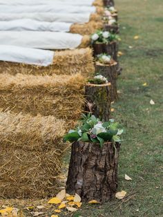 rows of hay bales lined up with flowers and greenery on them, along the grass