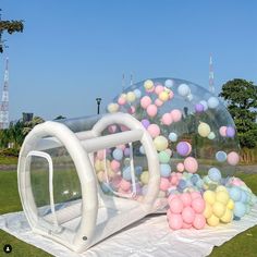 an inflatable bubble filled with balloons on top of a white cloth covered field