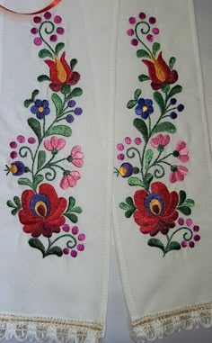 two white gloves with colorful flowers and lace on the bottom one has a red ribbon