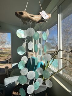 a wind chime hanging from the side of a window next to a tree branch