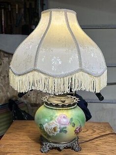 a lamp that is sitting on top of a table with a flowered vase underneath it