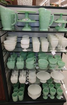 the shelves are filled with green and white dishes