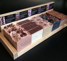 an assortment of different types of chocolates on display in a wooden tray with information