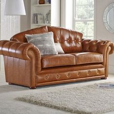 a brown leather couch sitting on top of a white rug